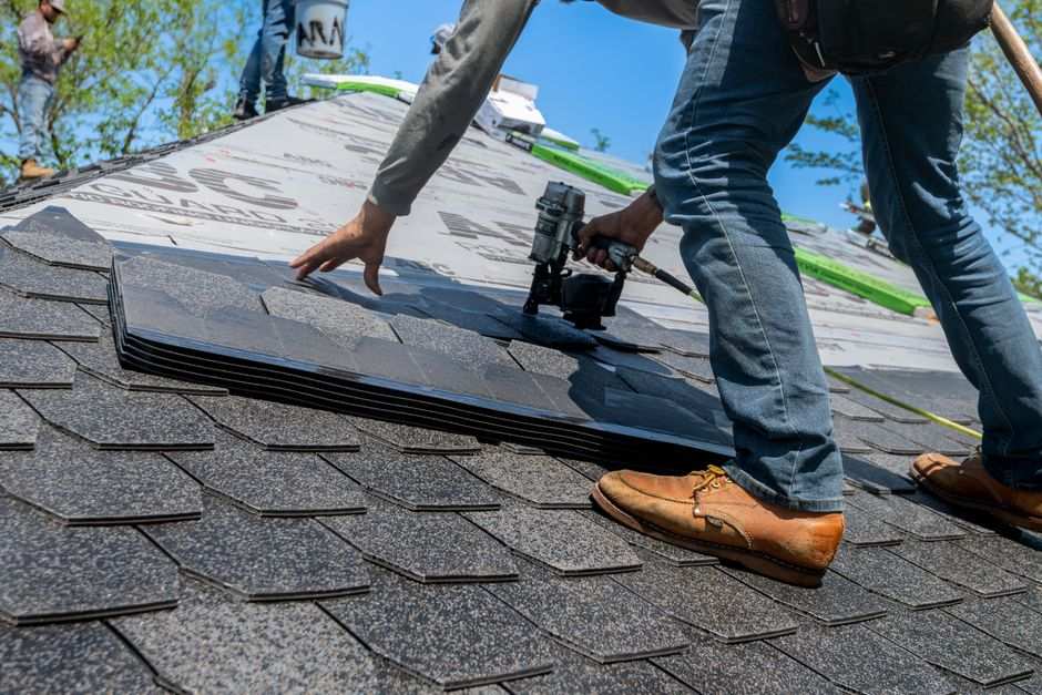 Roofer installing asphalt shingles on a residential roof replacement