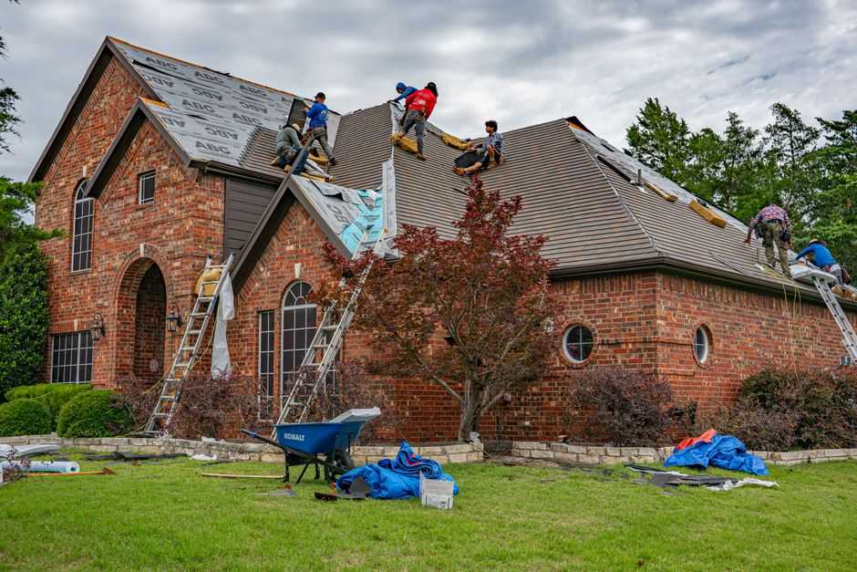 Roofer inspecting shingles and flashing during a free roof inspection